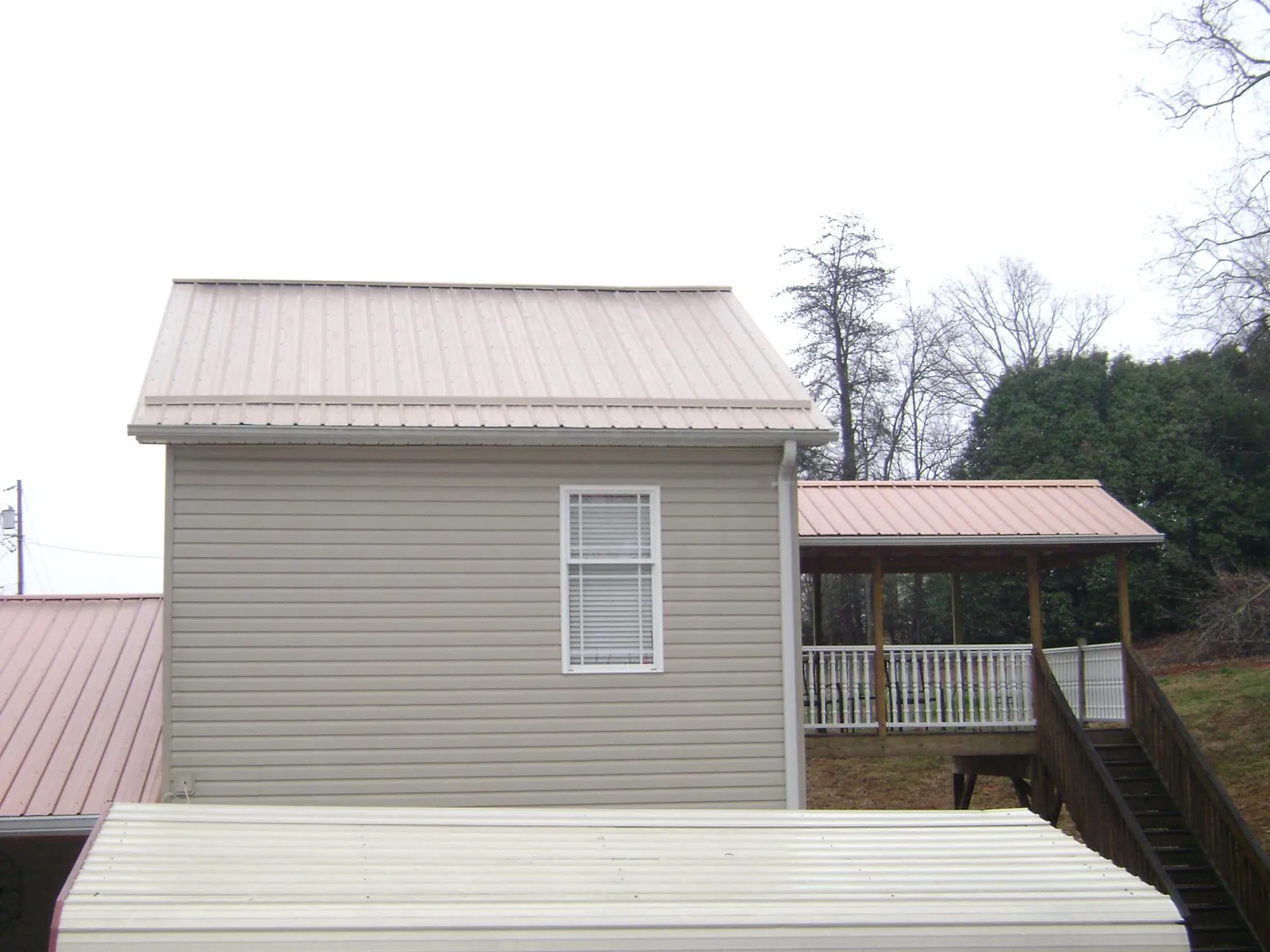 Tan metal roofs on a two story addition and attached porch, from a Roof Replacement job in Kaneohe