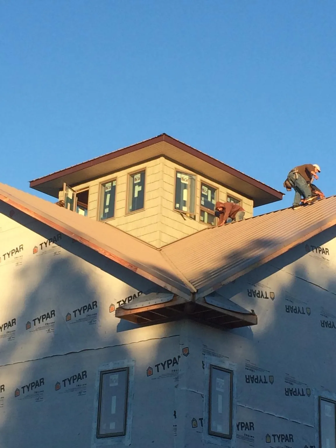 Roofers working around a rooftop cupola on a new metal roof at sunset — Roof Waterproofing in Kaneohe by Roofing Brothers